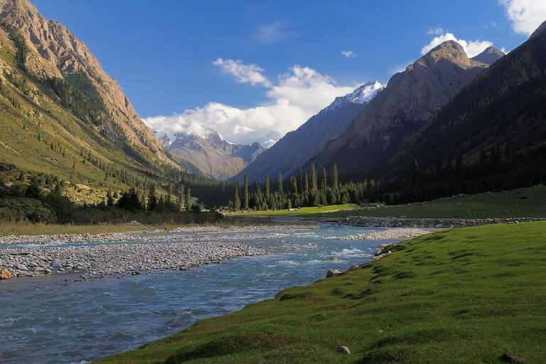 Равнинное поле с рекой среди гор в ущелье Барскоон