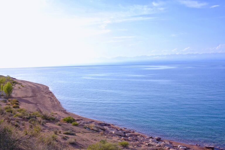 Голубо-синие озеро Иссык-Куль, с каменистым берегом